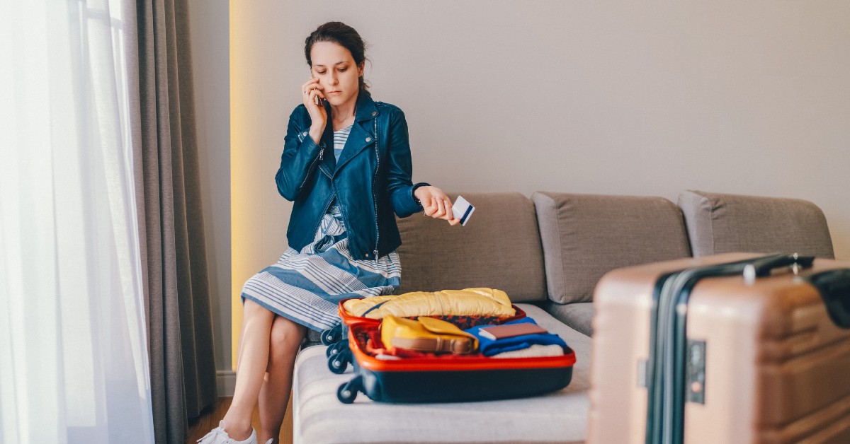 Woman on phone with bank while packing for a trip